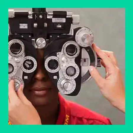 Man looking through an auto phoropter for an eye exam